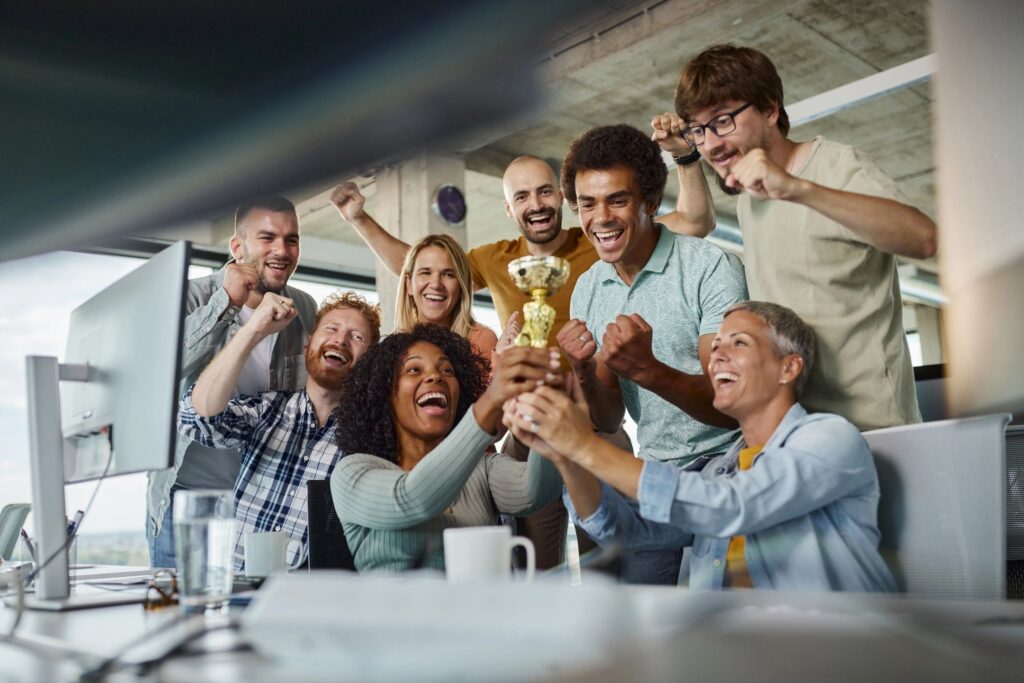 Group of cheerful colleagues celebrating winning a trophy for their work.